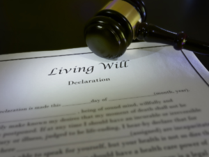 Một người lớn tuổi đang tự tay viết di chúc tại nhà dưới sự chứng kiến của hai người làm chứng.